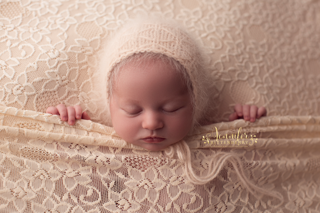 newborn infant in sleepy pose on light peach fabric