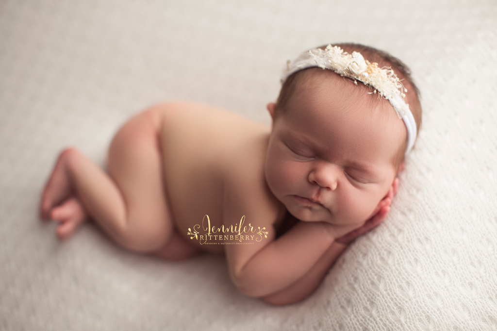 newborn baby posed on white fabric in side sleeper pose