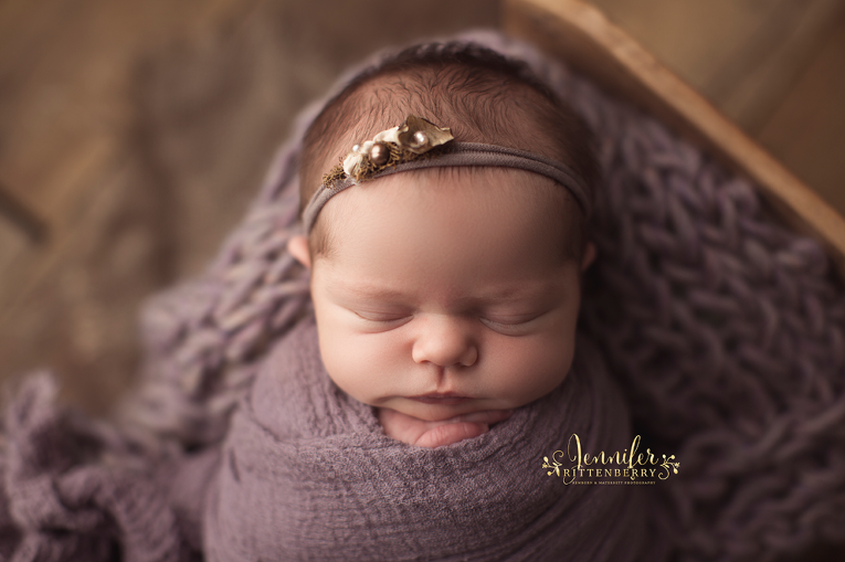 newborn infant posed on purple blanket