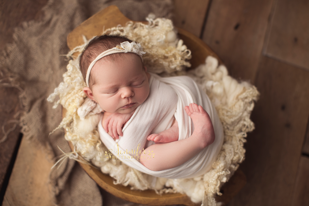 newborn infant posed in wood bowl